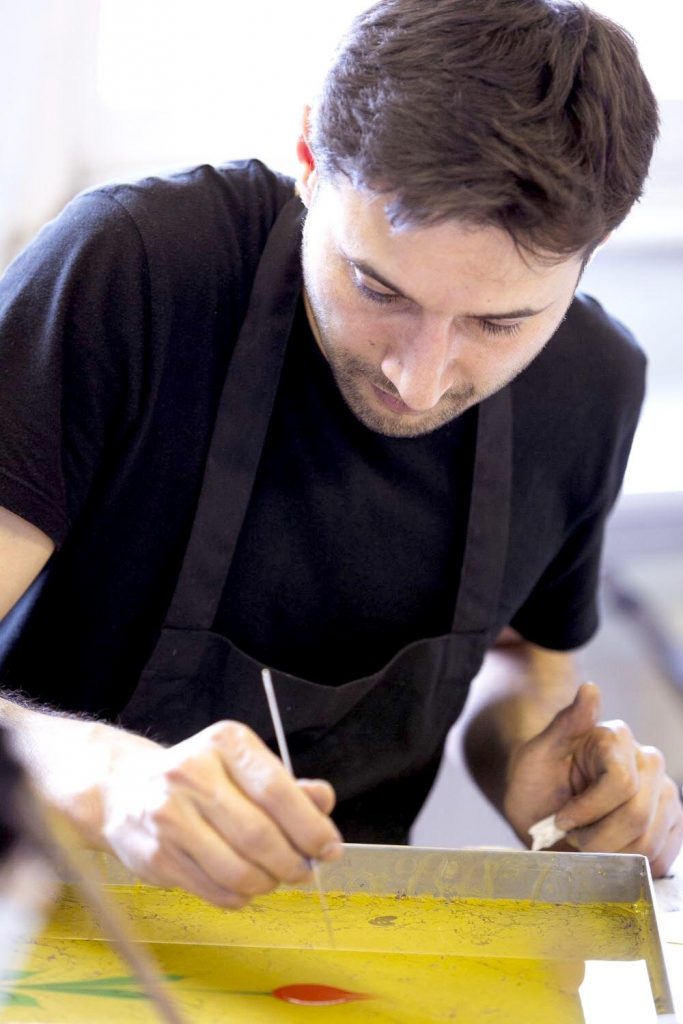 artist creating yellow painting on water